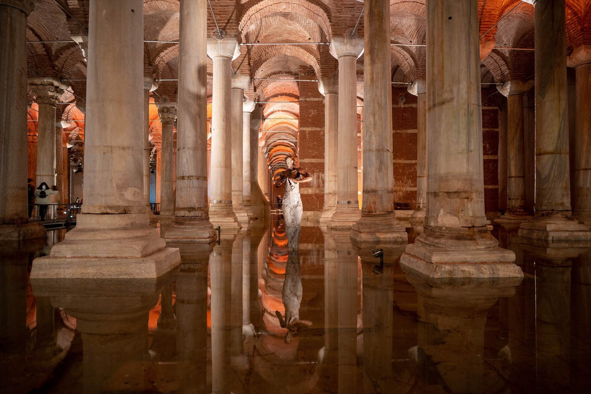 Una escultura contemporánea reflejada en el agua entre las columnas de la cisterna